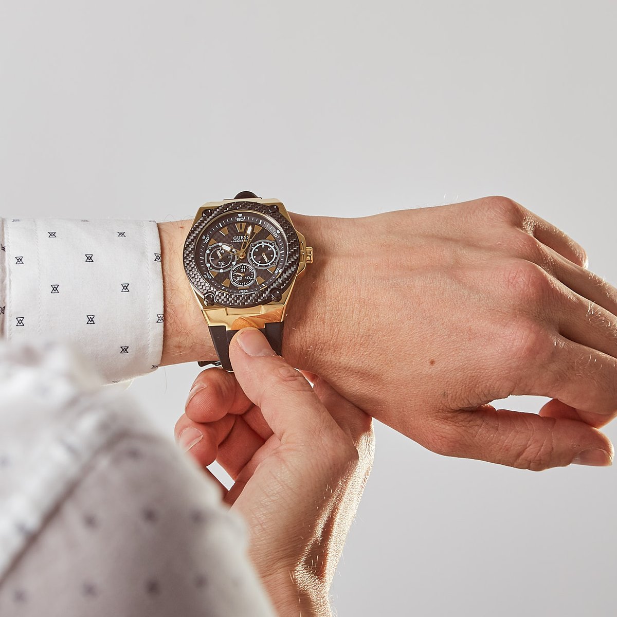 Guess Legacy chronograph watch on wrist showing gold case and black dial