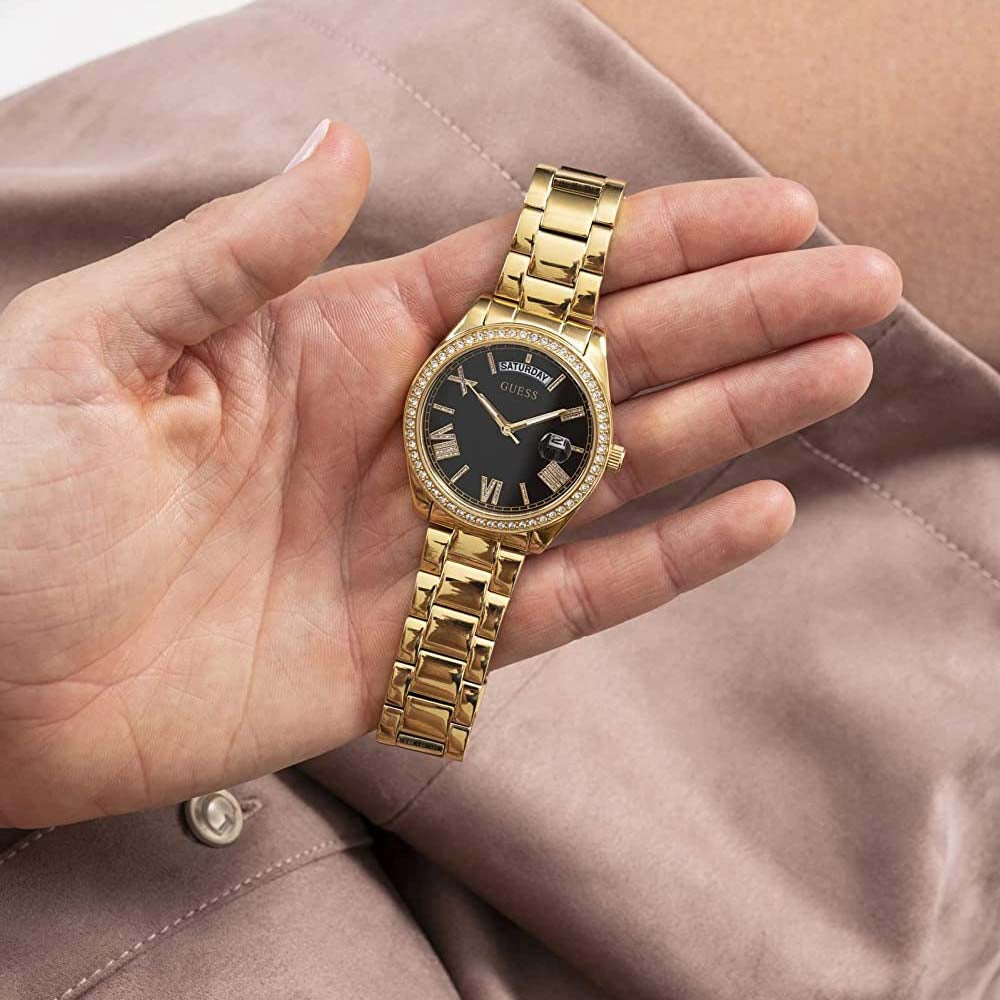 Guess Luna gold tone watch worn on wrist showing black dial and crystal bezel