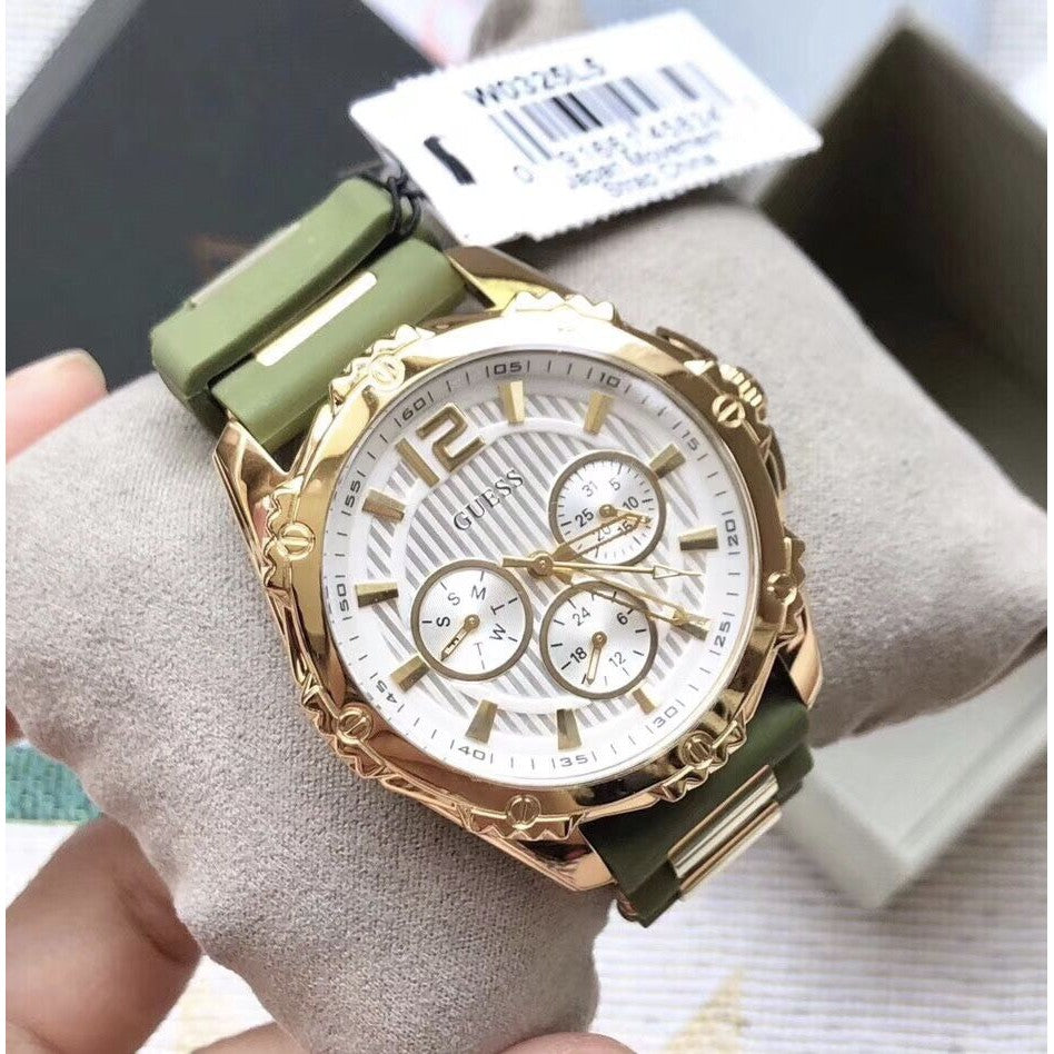 Guess W0325L5 watch on wrist displaying gold case and green silicon strap with gold accents