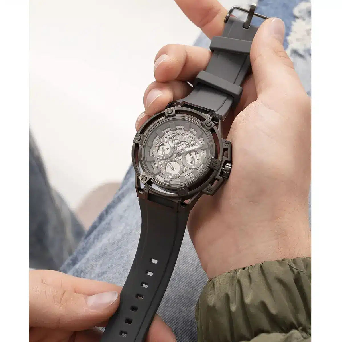 Guess Matrix watch held in hand showing gunmetal skeleton dial and rubber strap