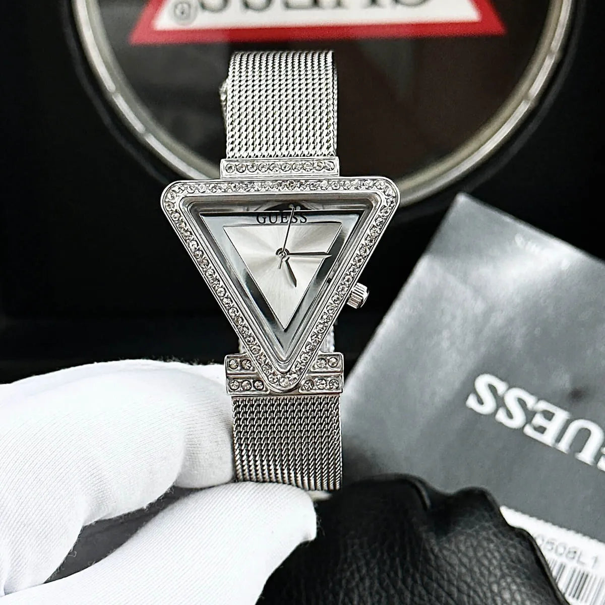Guess Fame watch with crystal-set triangular case worn on wrist with packaging visible