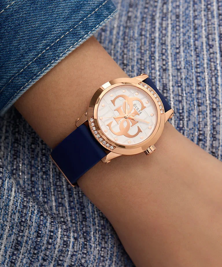 GUESS rose gold ladies watch worn on wrist with navy blue strap and decorative dial