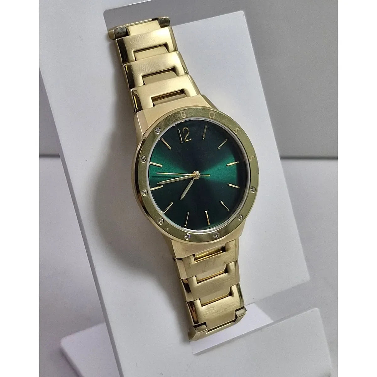 Hugo Boss gold watch with green dial displayed on white stand