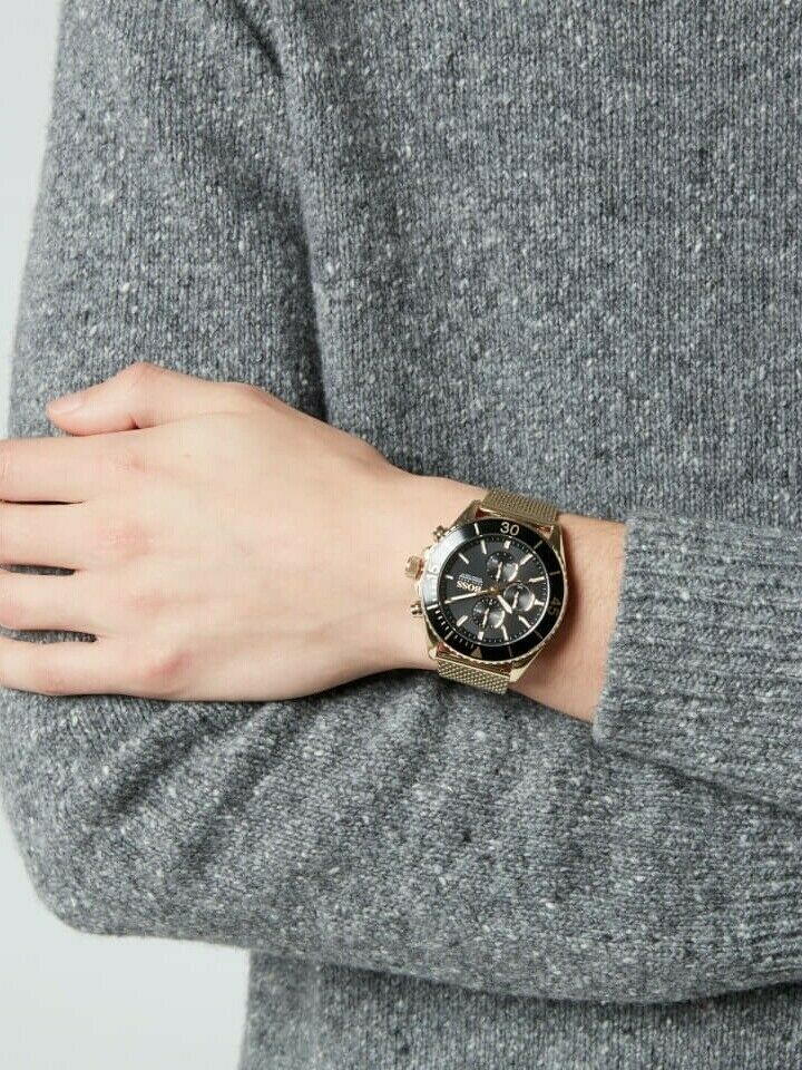 Hugo Boss watch with black dial and gold mesh strap on wrist over gray sweater