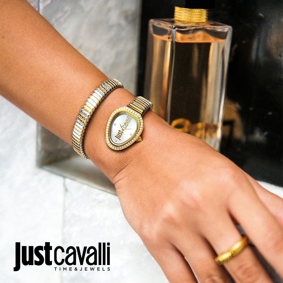 Just Cavalli Snake watch worn on wrist with stacked metal bracelets next to fragrance bottle