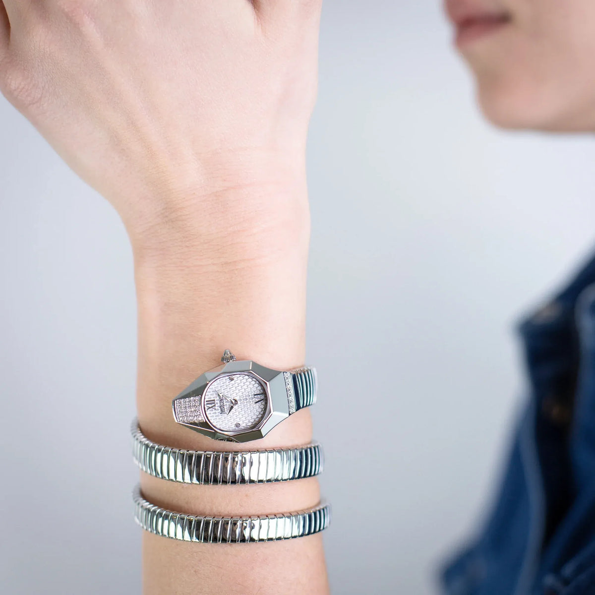 Just Cavalli Snake silver watch worn on wrist with stacked coiled snake bracelets