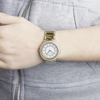 Michael Kors Kerry watch worn on wrist showing white mother-of-pearl dial and gold-tone bracelet