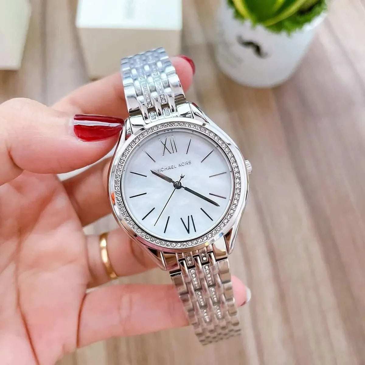 Michael Kors Mindy MK7075 watch held in hand showing full face with white dial and silver strap