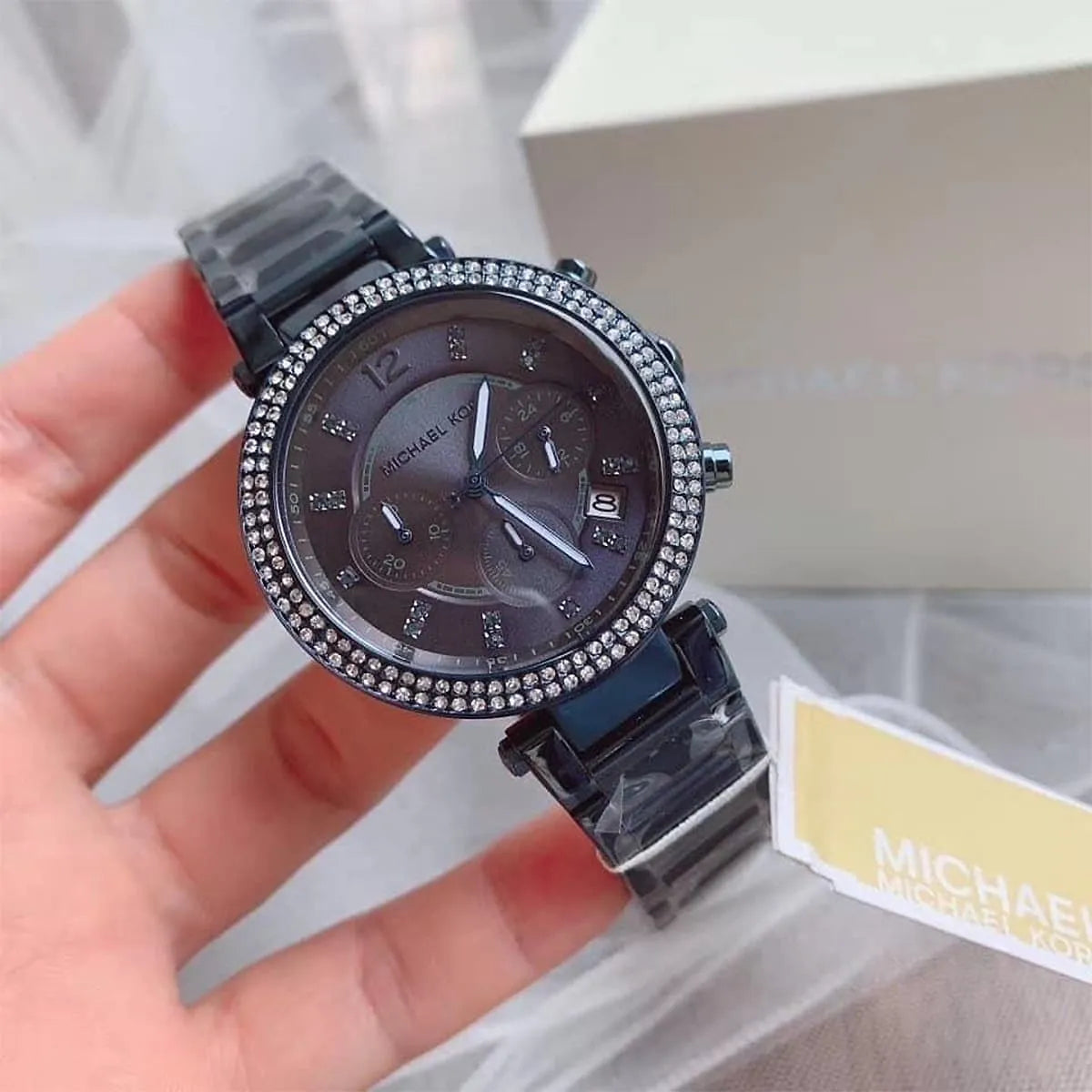 Michael Kors Parker MK6418 with crystal bezel displayed in hand on packaging