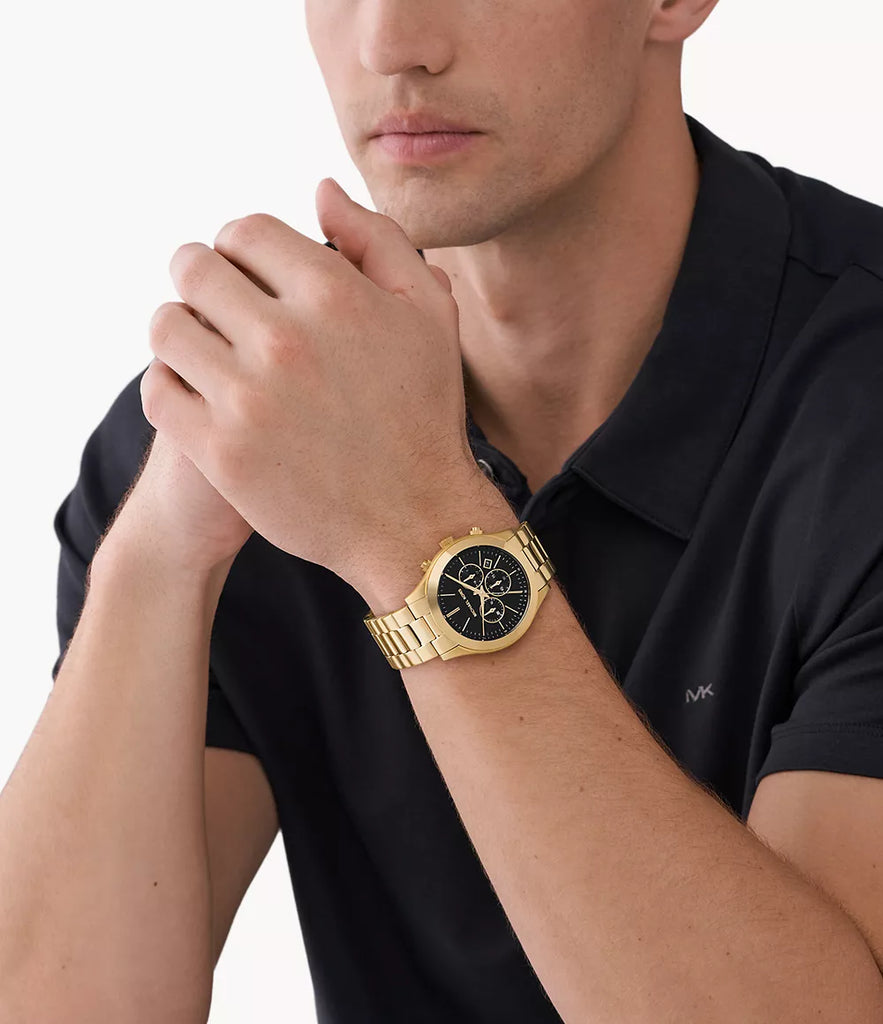 Michael Kors Slim Runway gold-tone chronograph watch worn on male wrist with black dial and subdials