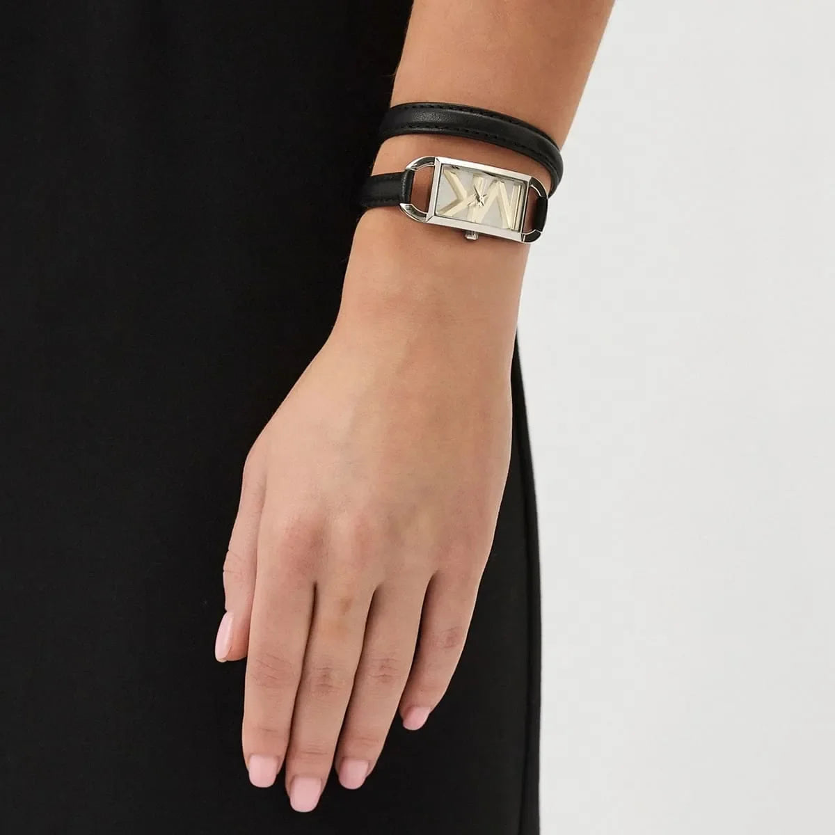 Mini Empire watch worn on wrist with black leather strap and silver case with gold X dial