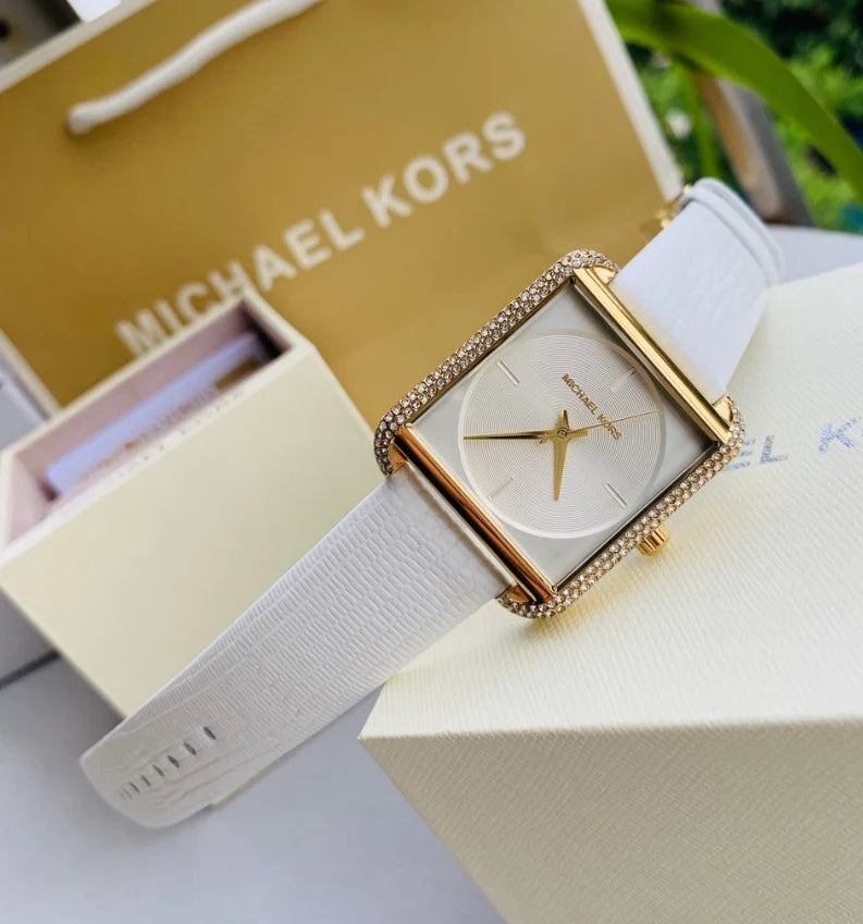 Michael Kors Lake Glitz watch worn on wrist with white leather strap and Michael Kors box in background