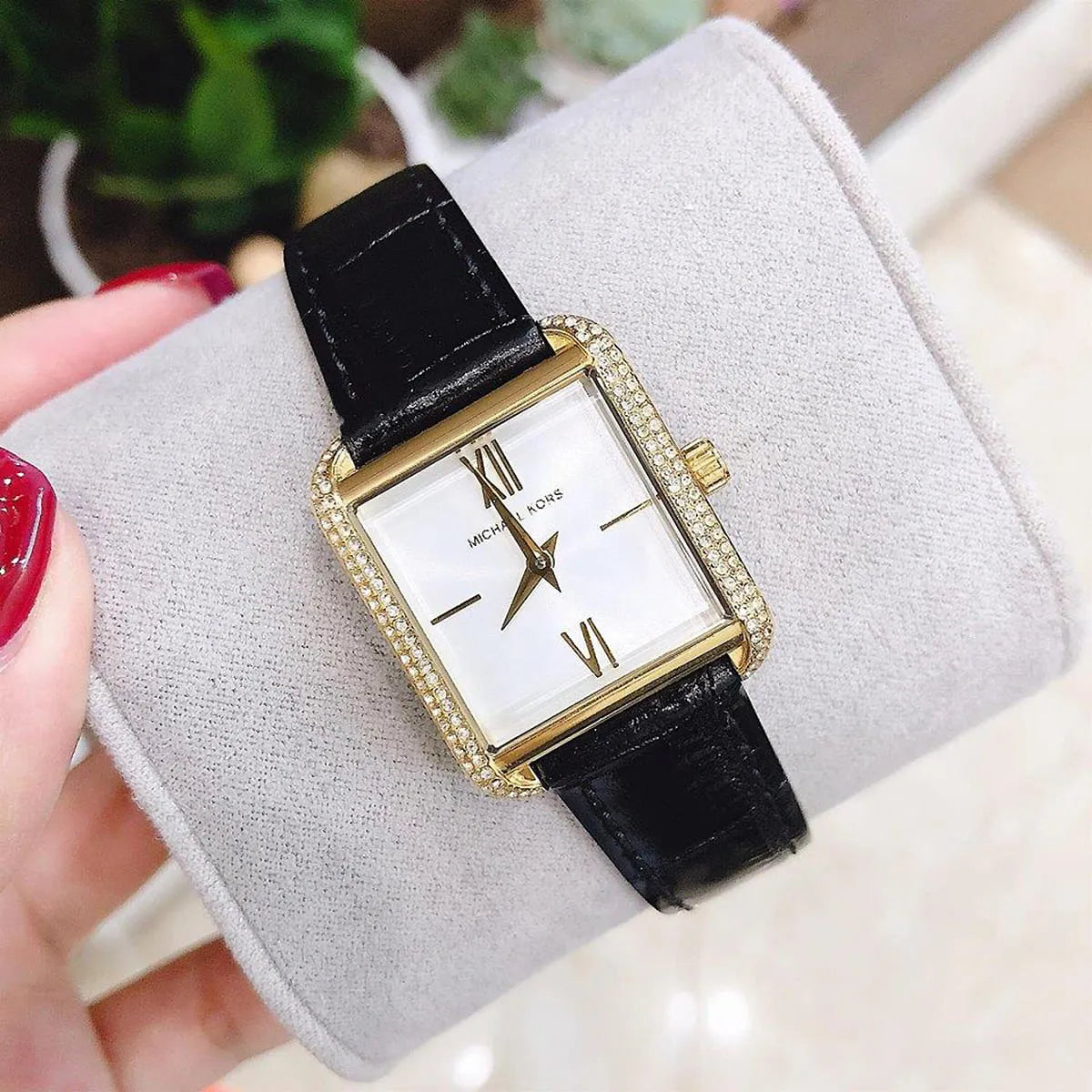 Close-up of Michael Kors Lake MK2762 watch on cushion showing square gold case, crystals, and white dial