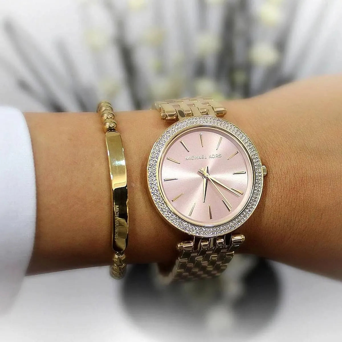 Michael Kors Darci rose gold women's watch worn on wrist with gold bangle bracelet
