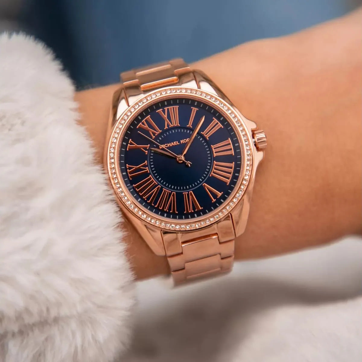 Michael Kors Kacie rose gold watch worn on wrist with blue dial and crystal bezel