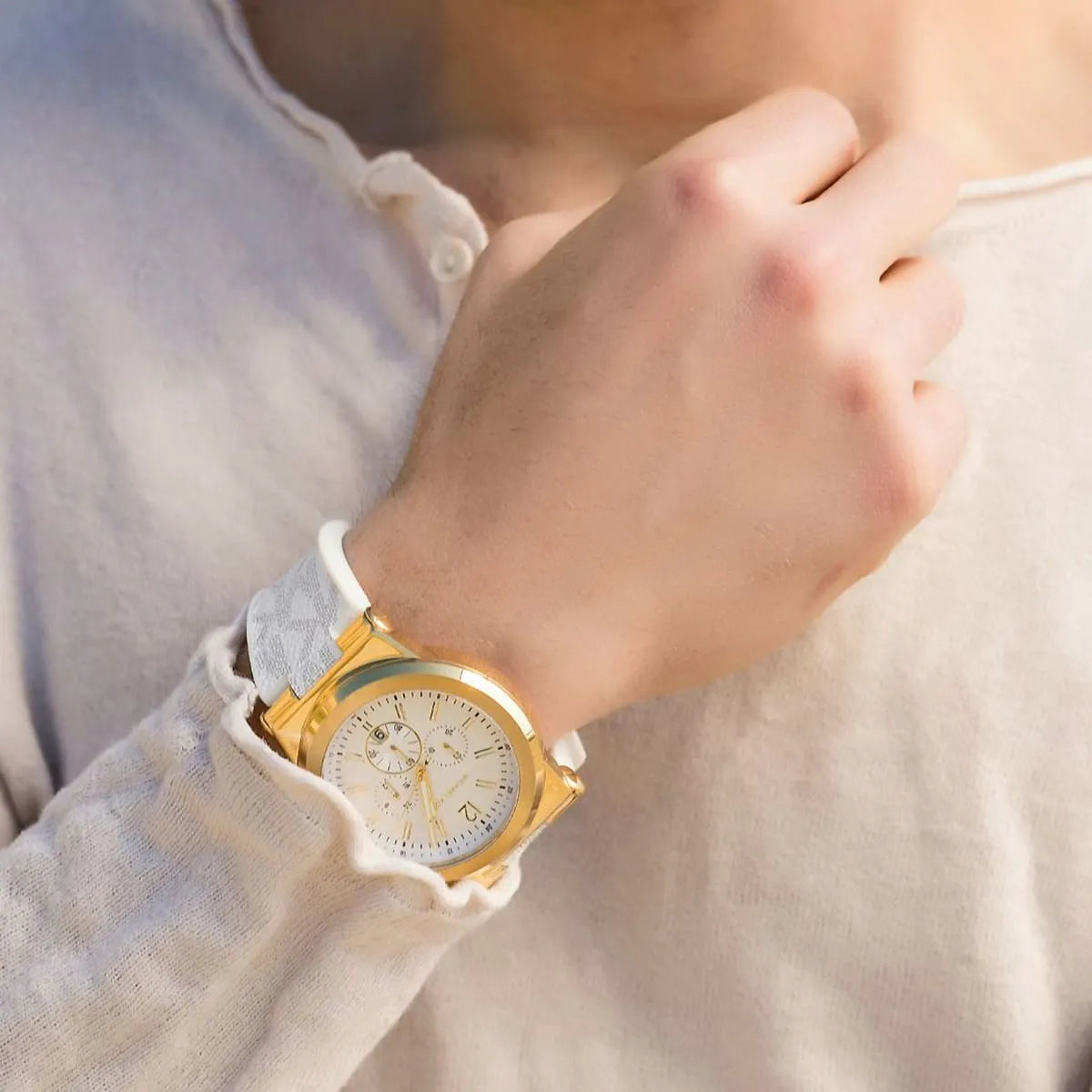Michael Kors Dylan chronograph watch worn on wrist with white strap and gold-tone case