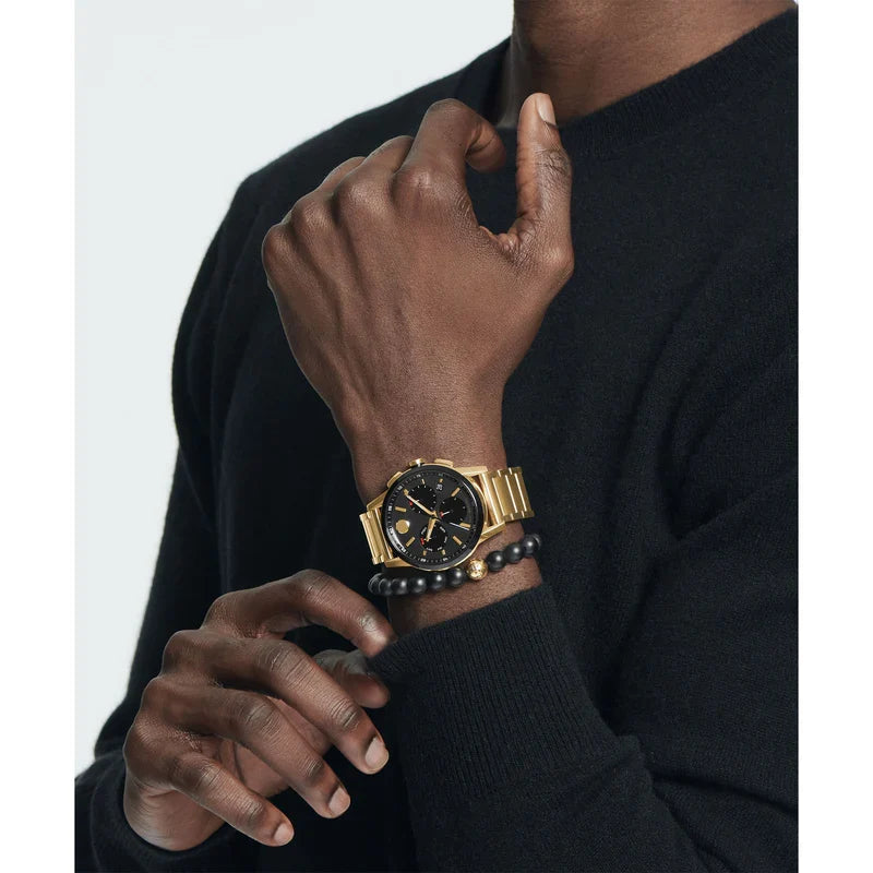 Movado gold steel chronograph watch worn on wrist with black dial visible