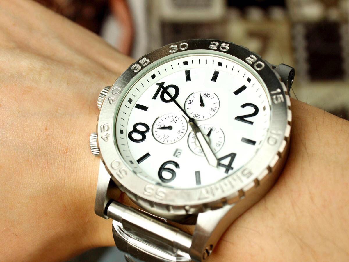 Nixon 51-30 chronograph watch worn on wrist showing white dial and stainless steel band