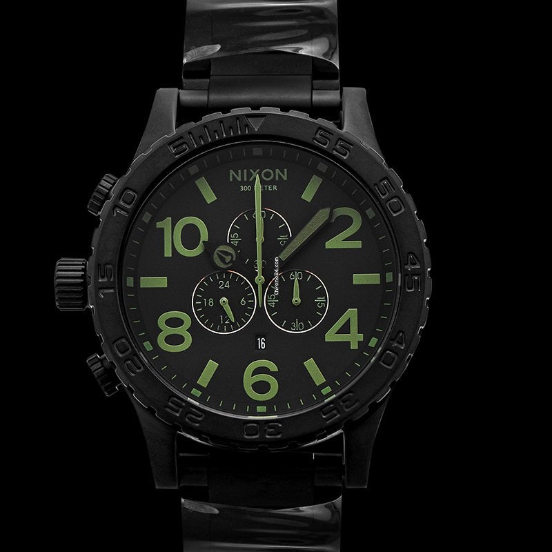 Angled view of Nixon 51-30 Surplus watch showing matte black case, dial with lime accents, and metal band