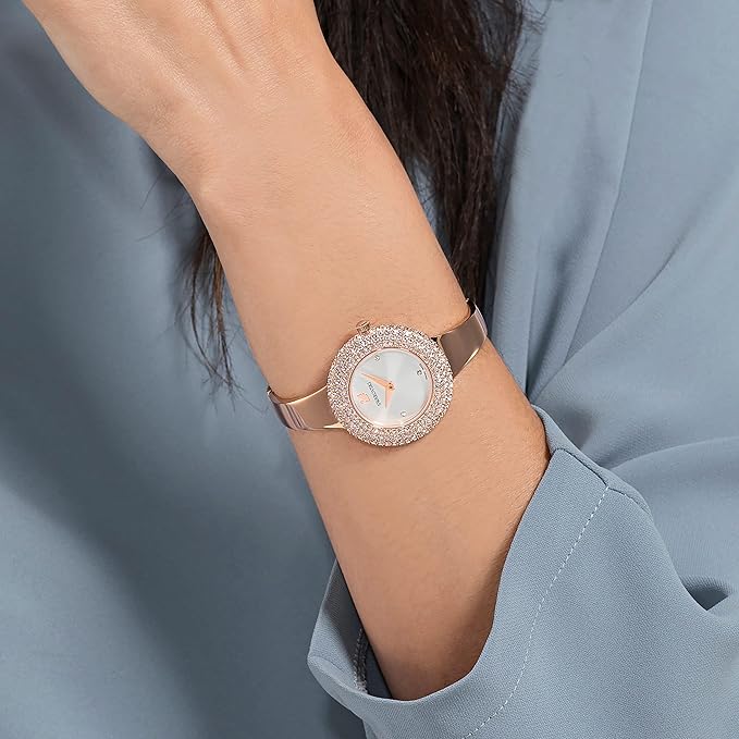 Swarovski crystal rose gold watch worn on wrist with white dial and rose gold bangle strap