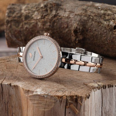 Swarovski Attract women's watch on wood surface, displaying bicolor rose gold and silver metal bracelet