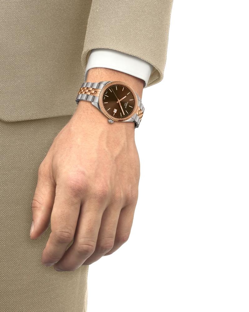 Tissot Ballade brown dial watch on men's wrist with two-tone bracelet