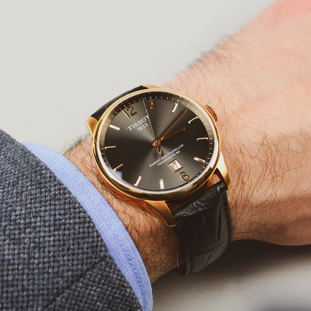 Tissot Chemin des Tourelles watch worn on wrist with rose gold case and black strap