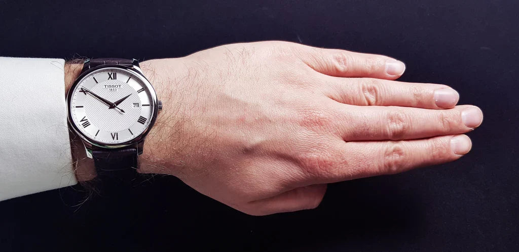 Tissot T-Classic Tradition watch worn on wrist showing silver case with brown leather strap