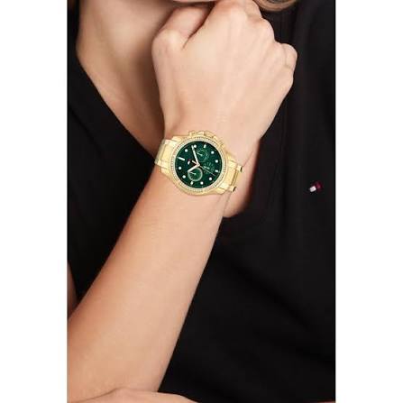 Gold chronograph watch with green dial worn on woman's wrist