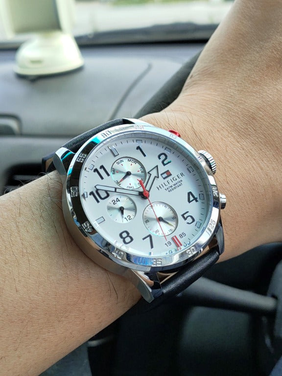 Tommy Hilfiger multi-function watch worn on wrist showing white dial and black leather strap