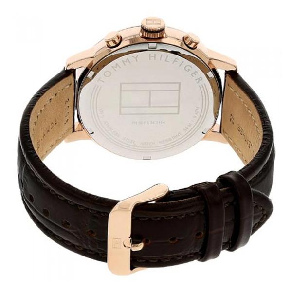 Case back view showing Tommy Hilfiger branding and model number on rose-gold tone case with brown leather strap
