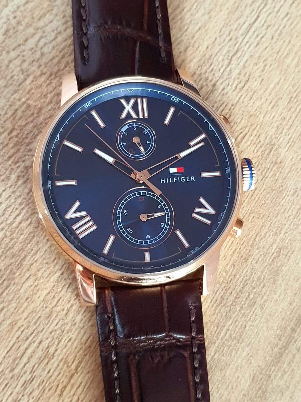 Tommy Hilfiger watch worn on wrist displaying blue dial with Roman numerals and dual chronograph sub-dials