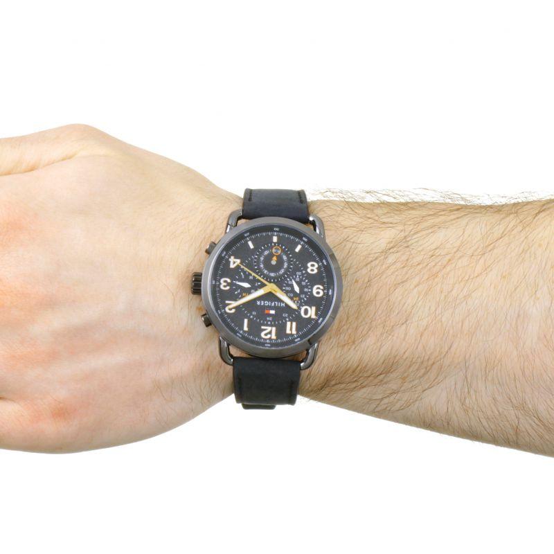 Tommy Hilfiger chronograph watch worn on wrist with black leather strap and black dial face