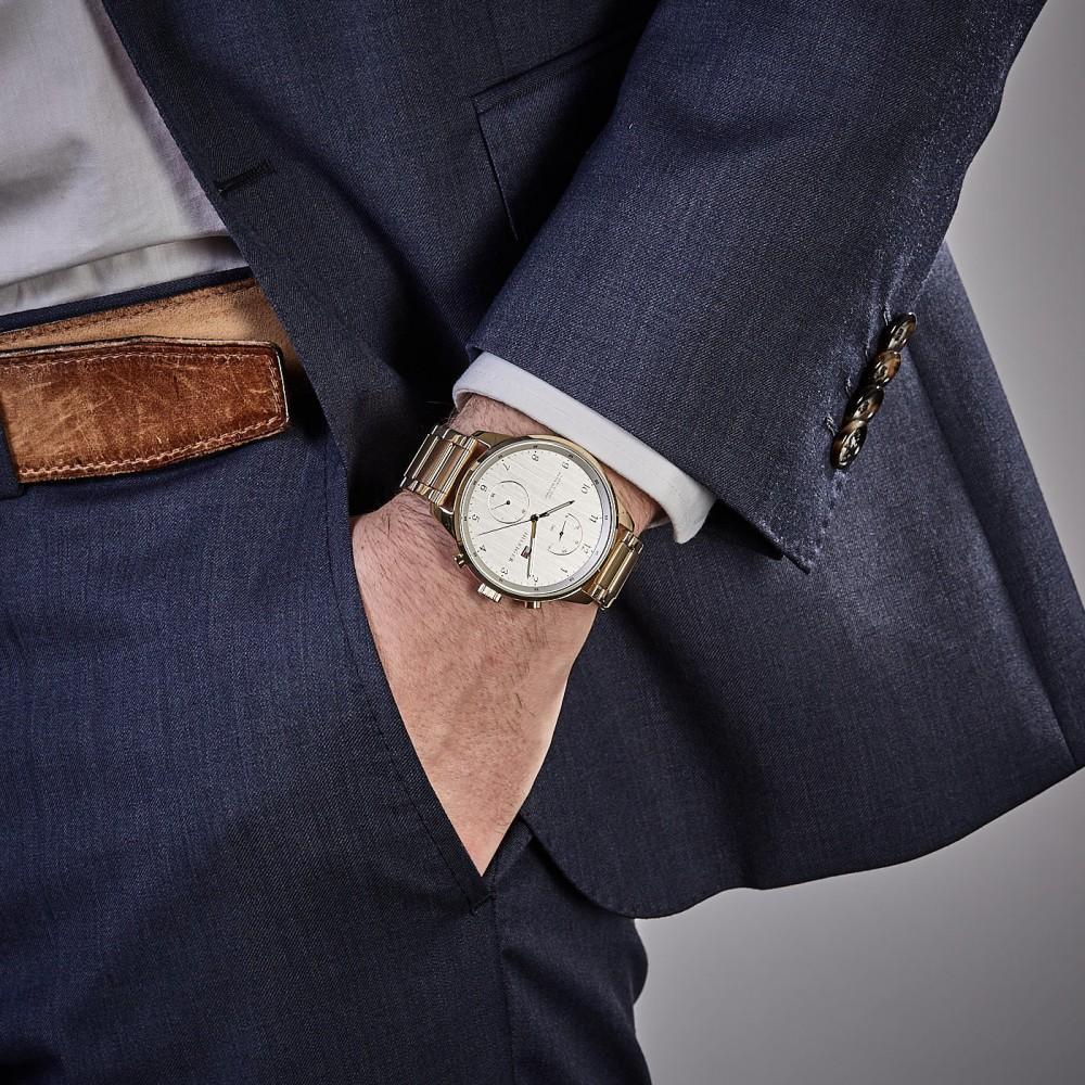 Tommy Hilfiger golden watch worn on wrist with formal navy suit jacket