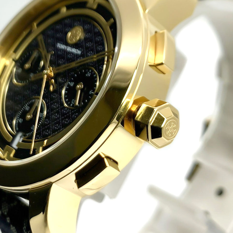 Close-up of navy dial featuring three subdials, gold-tone hands, Tory Burch logo, and chronograph pushers