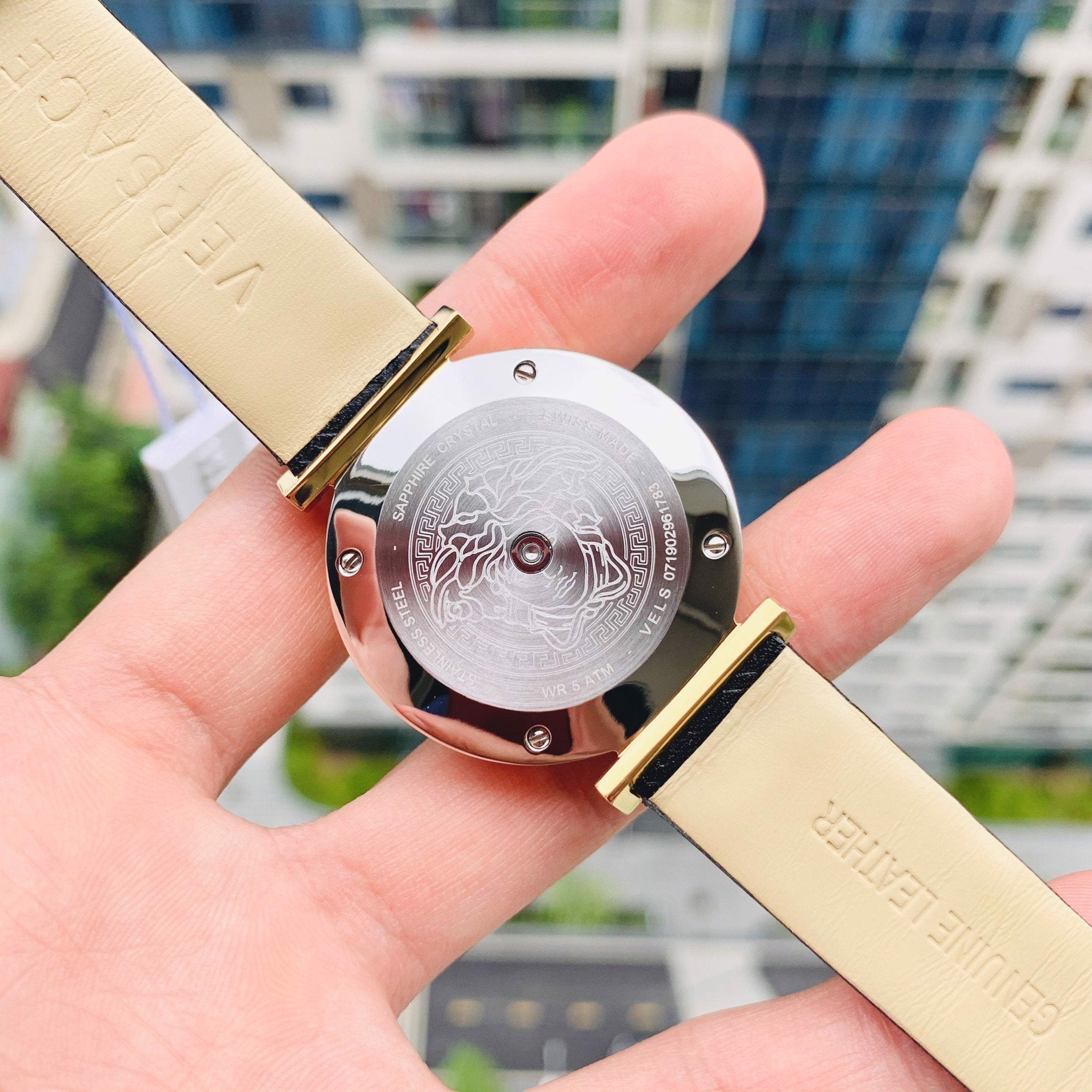 V-Twist watch held in hand showing caseback and white strap detail