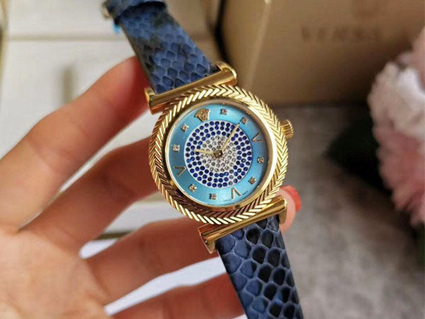 Close-up front view of Versace V-Motif watch face with diamond-set blue dial and gold bezel
