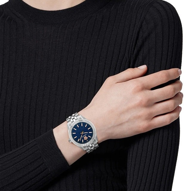 Versace V-Code women's watch worn on wrist with blue dial and silver stainless steel bracelet